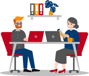 Two people sit at a desk with laptops in front of them